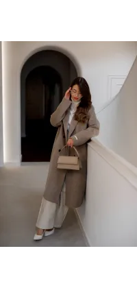 Пальто прямого крою з відкладним коміром та застібкою на гудзики. Відтінок — теплий бежево-сірий (тауп), одяг від Jador