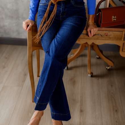 Темно-сині джинси з високою посадкою та розкльошеним низом, які візуально подовжують ноги та підкреслюють фігуру