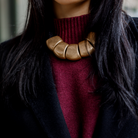 масивне жіноче кольє з великими металевими сегментами та м’якою текстурною стрічкою
